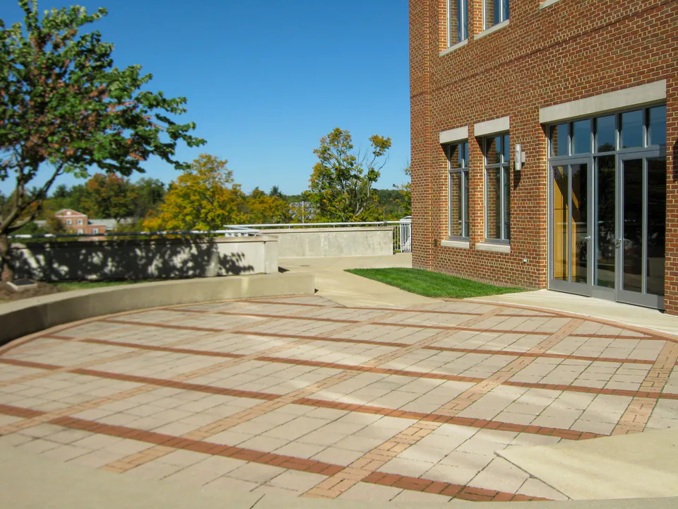 Campus plaza paving with brick bands, concrete walks, lawn edge, and brick building entry